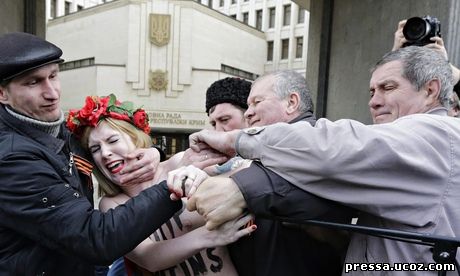 A Femen protester against Vladimir Putin's policies concerning Ukraine is detained near the Crimean parliament in Simferopol.