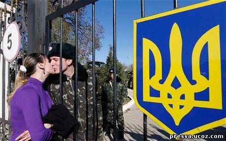 A woman kisses a Ukrainian serviceman through the gate by a military unit near an airfield in Crimea 