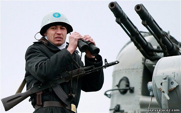 A Ukrainian sailor stands guard with his pair of binoculars on top of a Ukrainian navy ship at the Crimean port of Yevpatorya